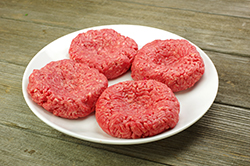 Four Raw Burgers on a Plate